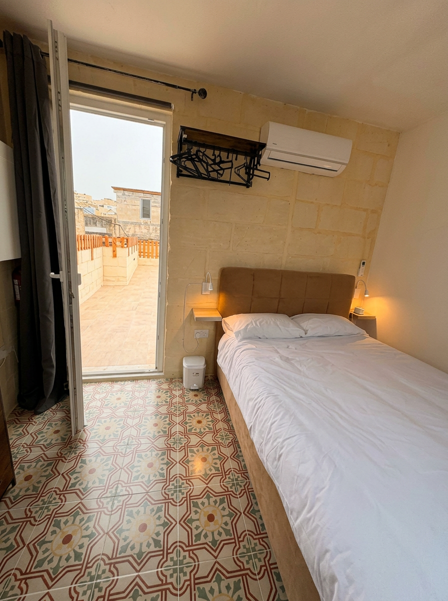 Bedroom with patterned Maltese tile floor opening onto a private rooftop terrace