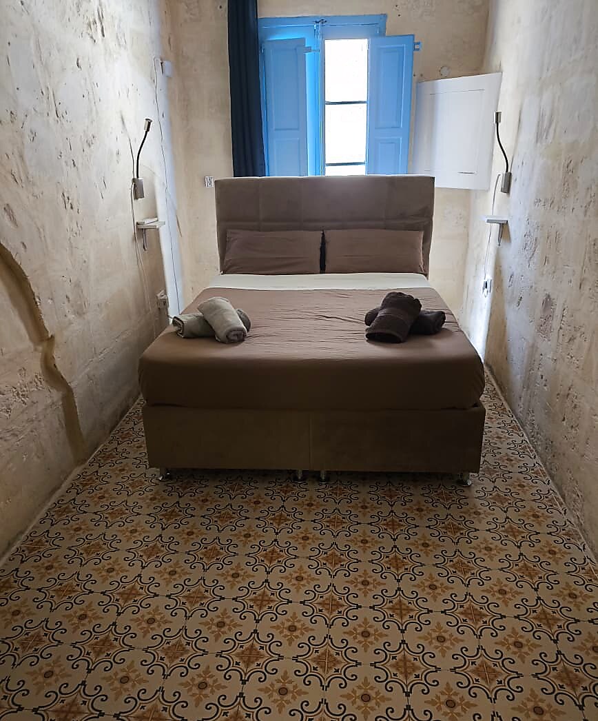 Restful bedroom with brown linens, blue shutters and decorative floor tiles