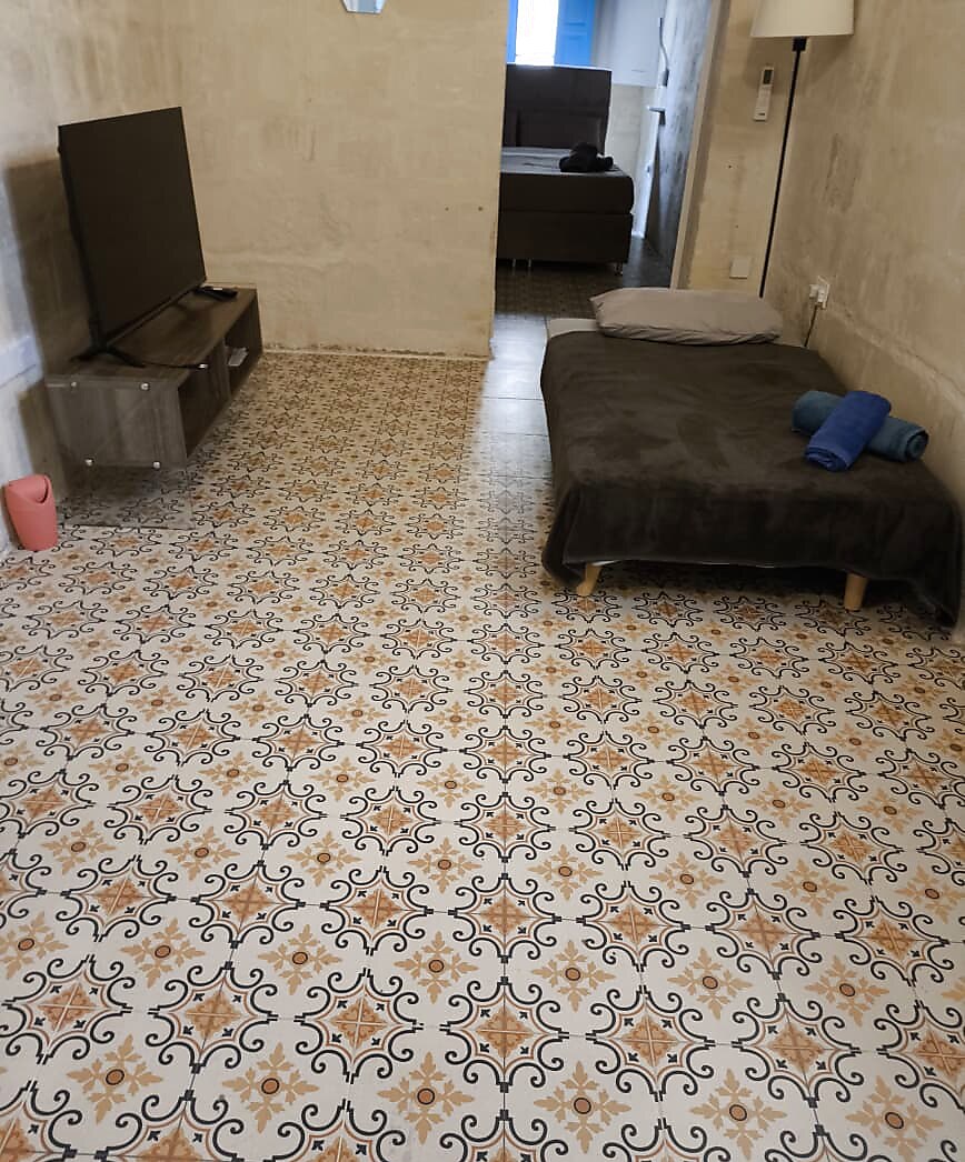 Spacious living and sleeping area with traditional Maltese tiles and stone walls