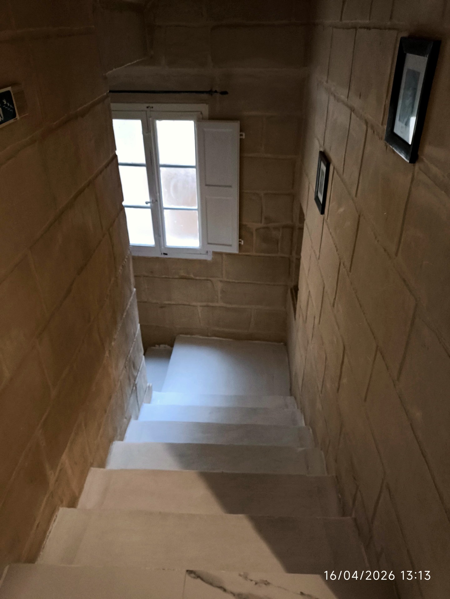 Limestone staircase with framed historic artwork and natural light